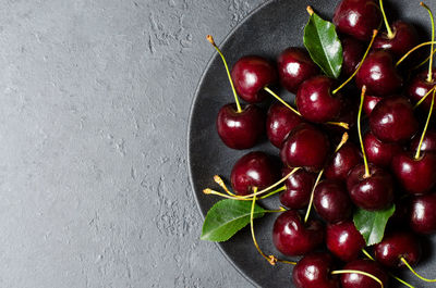 Lots of ripe cherries on a black plate. dark background