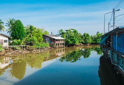 Reflection of trees and houses in lake against sky