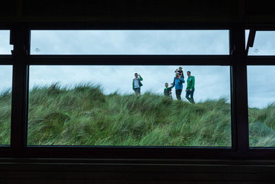 People working in farm against sky seen through window