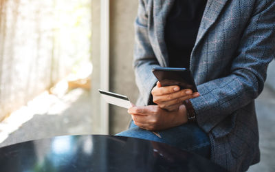 Midsection of man using mobile phone