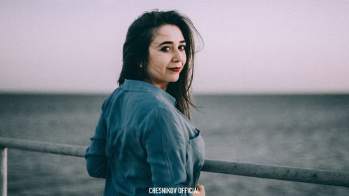 Portrait of young woman standing against sea