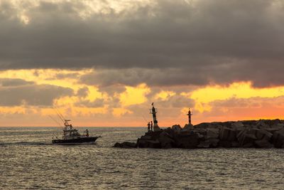Ship sailing on sea against sky during sunset
