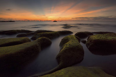 Scenic view of rocks in the sea during sunset