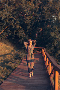 Woman standing on bridge at sunset