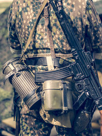 Midsection of soldier standing while carrying gun