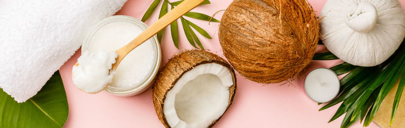 High angle view of coconut with leaves on pink background