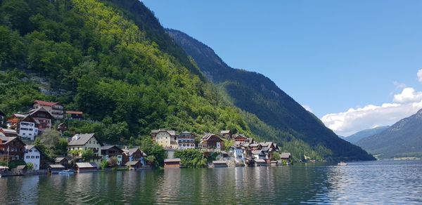 Houses by lake and mountains against sky