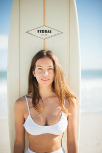 Young woman standing at beach against sky