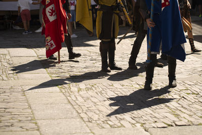 Low section of people walking on street in city