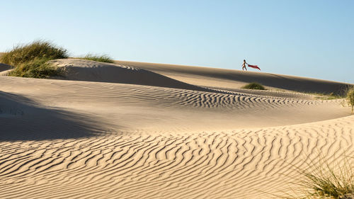 Distant view of woman walking on desert