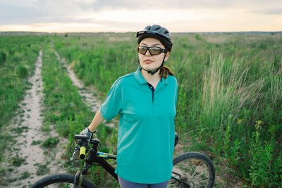 Portrait of young man riding bicycle on field