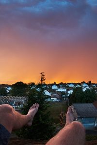 Midsection of man against orange sky during sunset