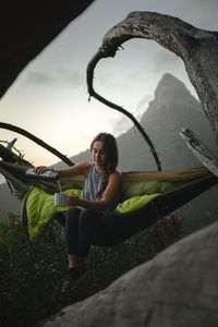 Portrait of woman sitting on plants against sky