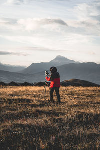 Full length of man photographing on field against sky