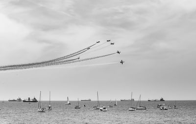 Sailboats in sea against sky