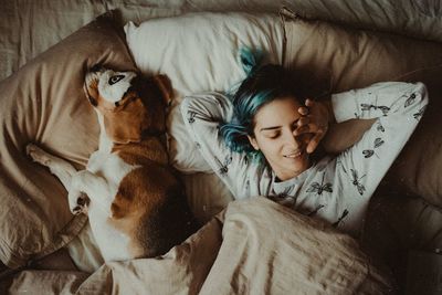 Directly above shot of woman with dog sleeping on bed at home