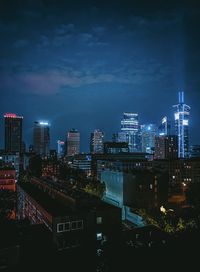 Illuminated buildings in city against sky at night