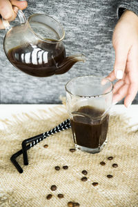 Midsection of woman pouring coffee in cup on table