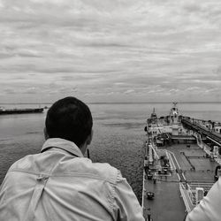Rear view of man looking at sea against sky