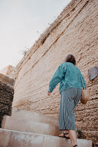 Rear view of woman walking against wall