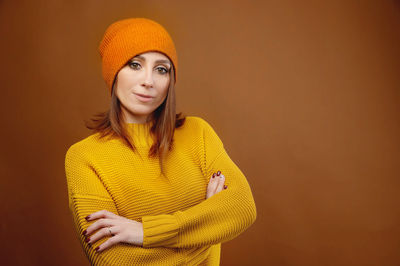 Portrait of smiling young woman standing against orange background