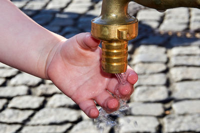 Cropped hand of child washing hand under faucet