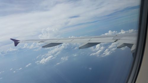 Close-up of airplane wing against cloudy sky