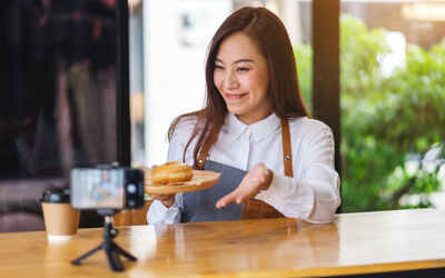 Smiling woman vlogging at cafe