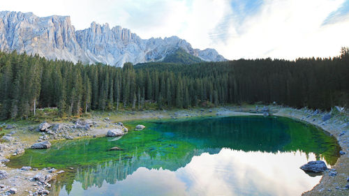 Scenic view of karersee amidst trees against sky