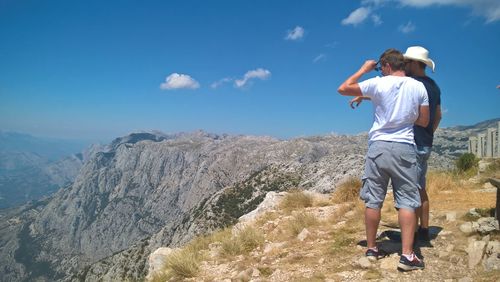 Rear view of man standing on mountain against sky