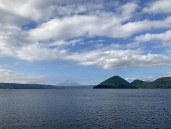 Scenic view of sea by mountains against sky