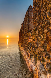 Close-up of rock on sea against sky during sunset