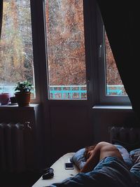 Shirtless man sleeping by window at home