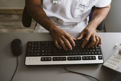 Male doctor typing on keyboard while sitting at desk