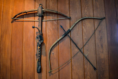 Low angle view of bow and arrow hanging on wooden wall