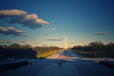 Group of people walking on road at sunset