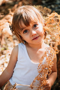 Portrait of cute girl holding plant parts in forest