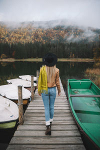 Rear view of woman standing on boat in lake