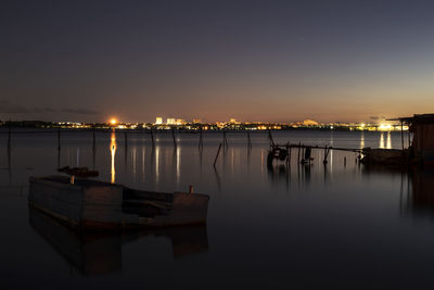 Sailboats moored in marina at sunset