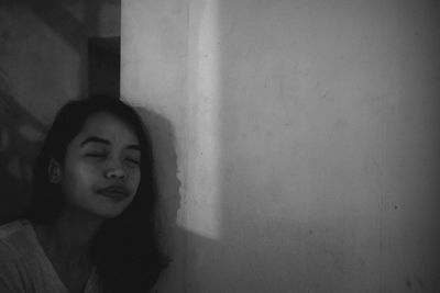 Portrait of young woman standing against wall