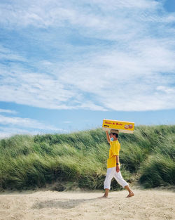 Full length of woman standing on beach against sky