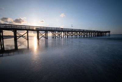 Pier over sea against sky during sunset