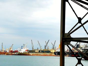 Cranes at harbor against sky