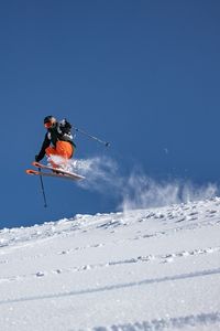 Person skiing on snowcapped mountain against clear sky