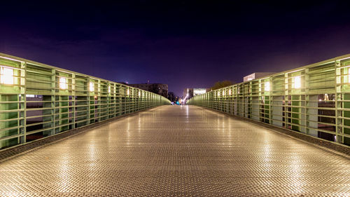 Illuminated footbridge against sky in city at night