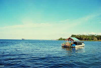 Boat sailing in sea against blue sky