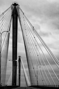 Low angle view of suspension bridge against cloudy sky