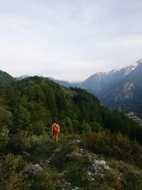 Rear view of man and plants on mountain against sky