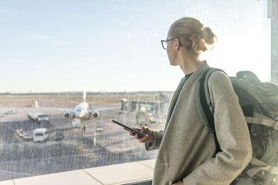 Young woman using smart phone against sky