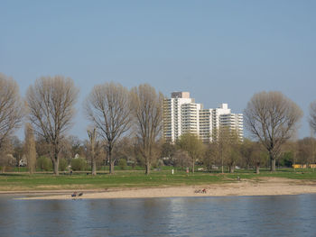 River by trees and buildings against clear sky